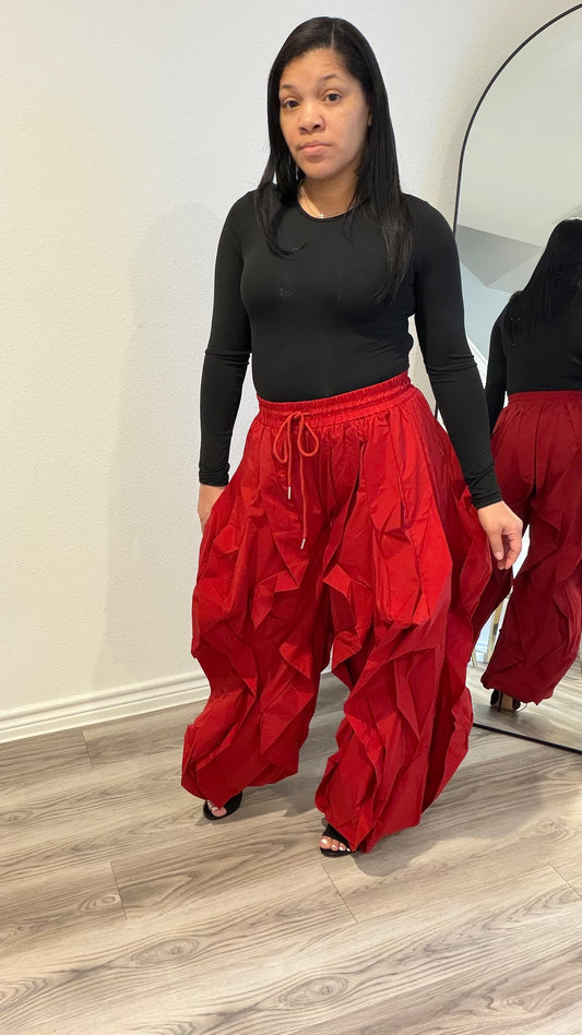 Woman wearing a fitted black long sleeve bodysuit with a smooth, second-skin silhouette paired with red statement pants.