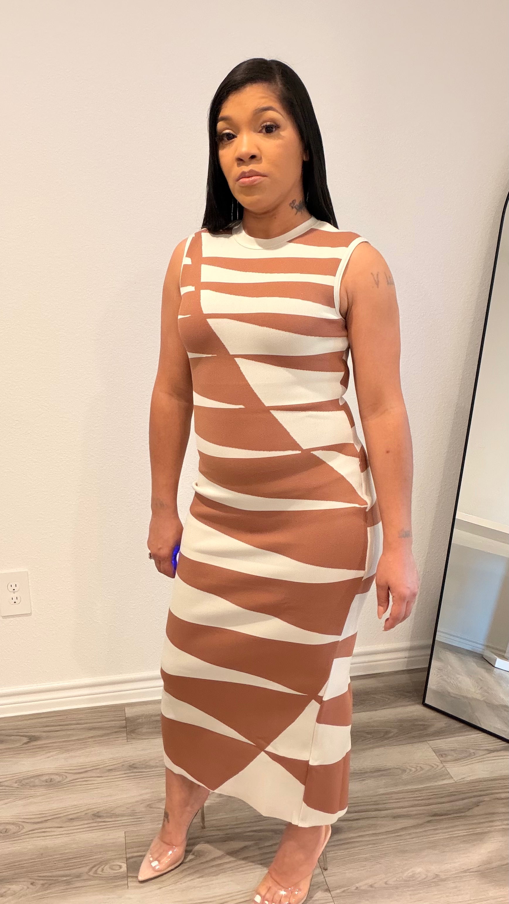 Woman wearing an abstract print column dress with a sleek, straight silhouette.