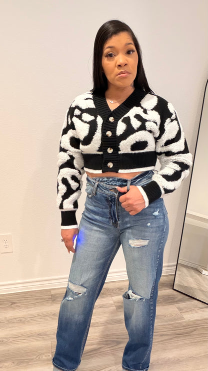 Woman wearing a cropped color-block cardigan layered over a fitted top.