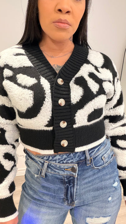 Woman wearing a cropped color-block cardigan layered over a fitted top.