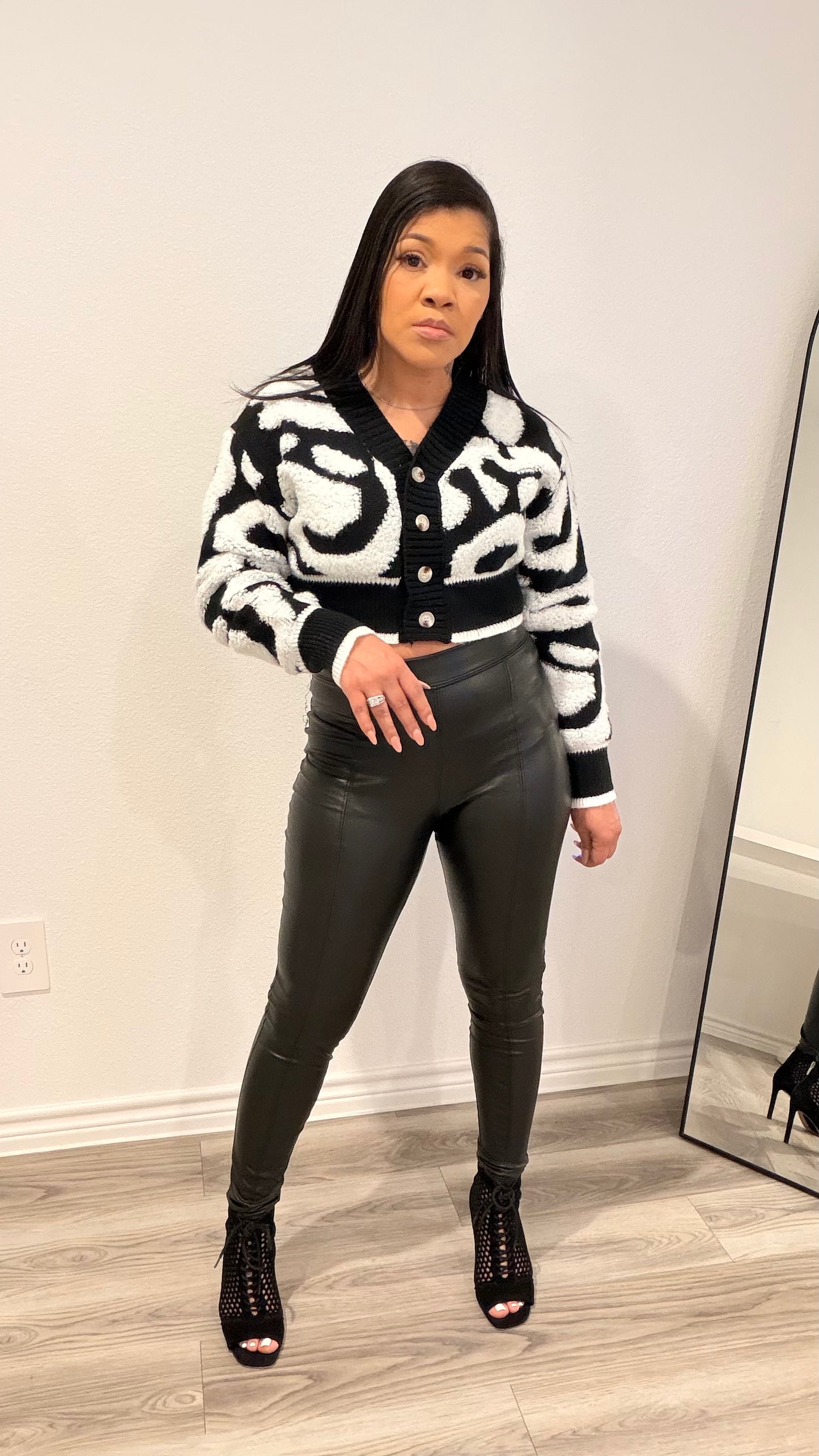 Woman wearing a cropped color-block cardigan layered over a fitted top.